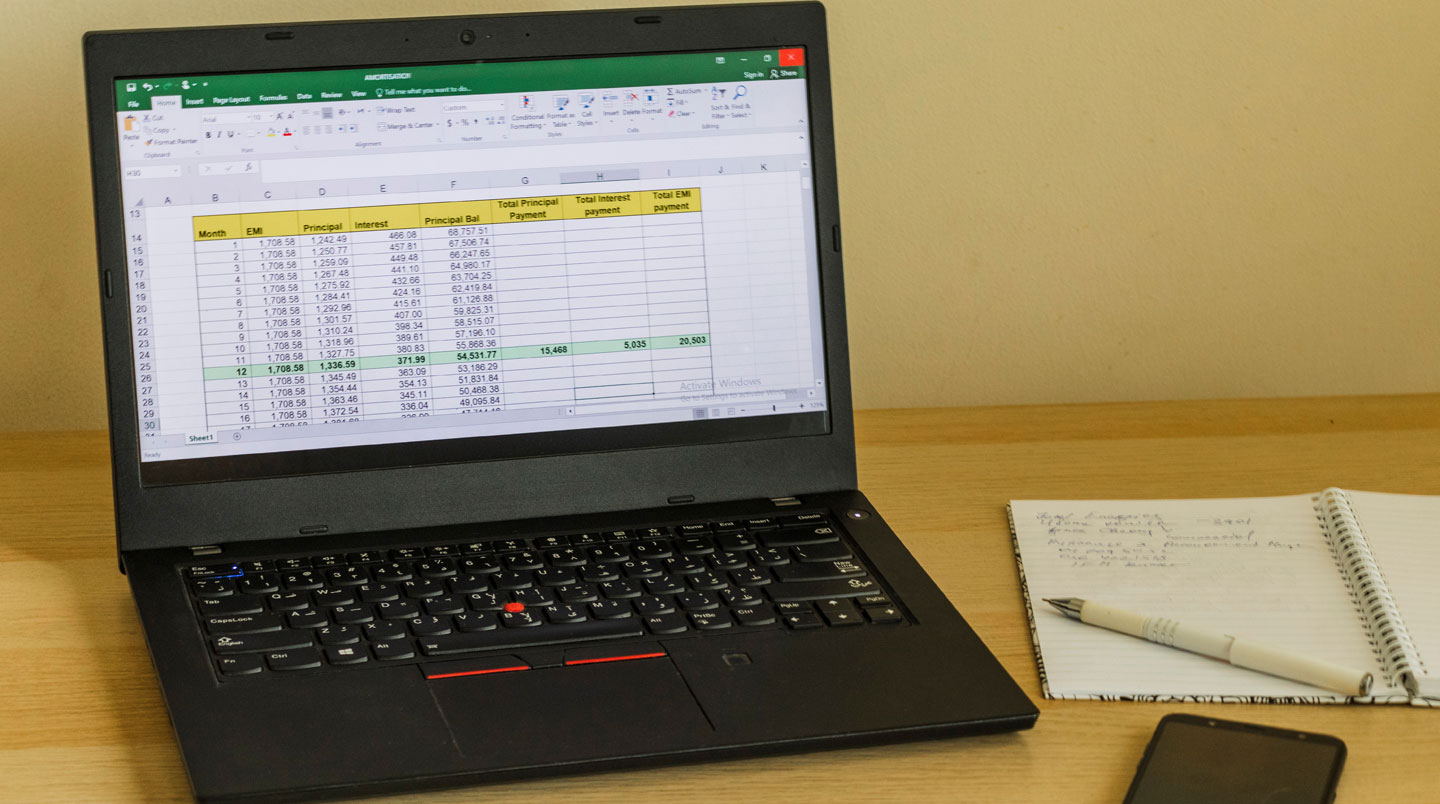 Bureau de responsable catalogue avec écran affichant plusieurs fichiers Excel ouverts, post-its colorés sur les bords, mains tapant sur clavier, suggérant une charge de travail intense de consolidation manuelle